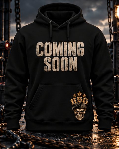 Black hoodie with Coming Soon across the chest and the RBG skull-in-beret on the hem, on a boat deck at dusk